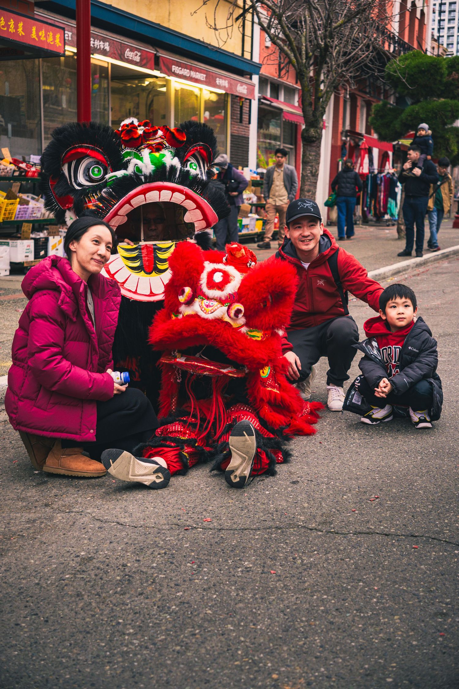 Candid shot of a family posing with dragon costume performers in the Awakening Chinatown Festival