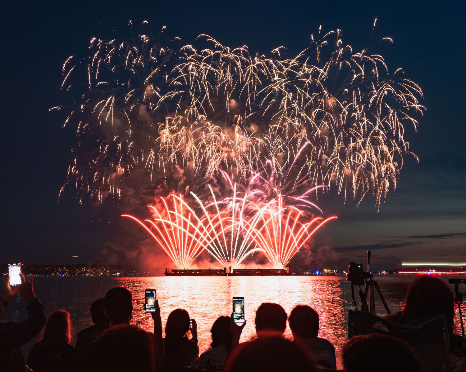 Vibrant red fireworks against deep navy sky at English Bay