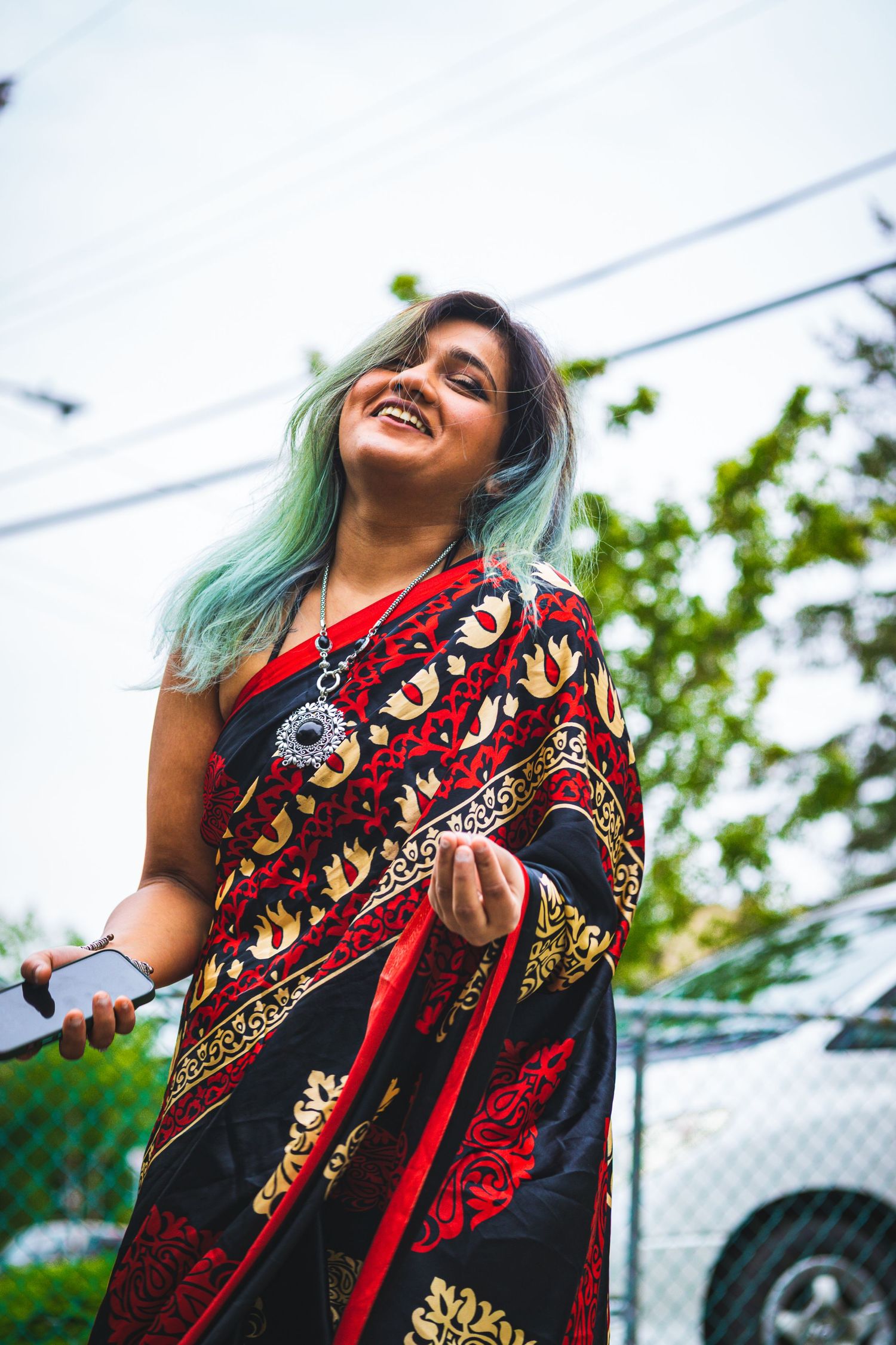 Candid shot of woman in red saree, laughing mid-movement in natural light in Victoria, Canada