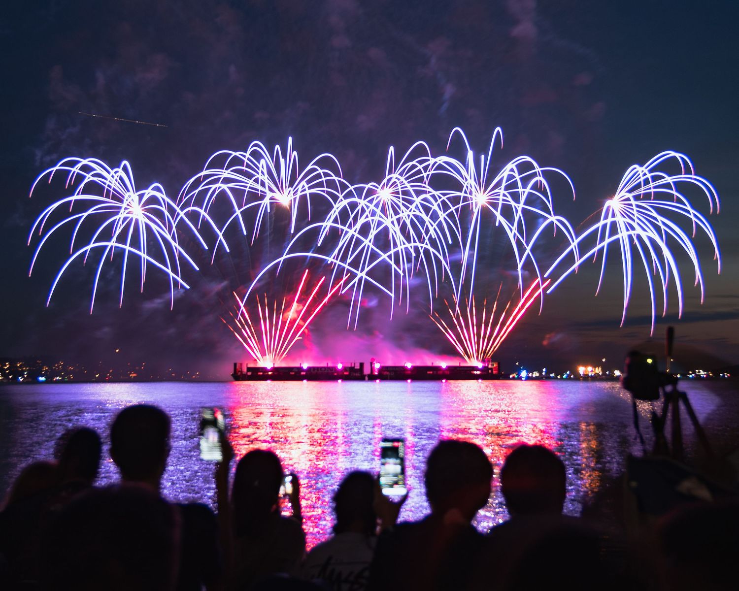Long-exposure photo of fireworks streaming through the sky in English Bay
