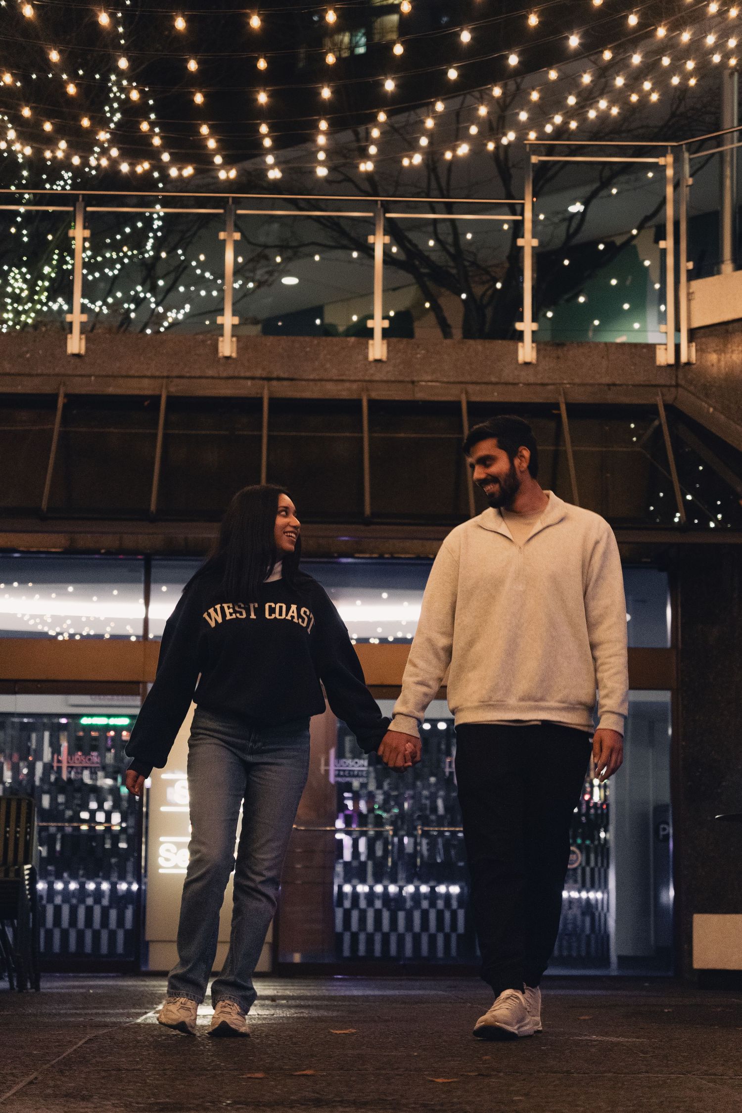 Candid moment of couple laughing under warm lights in Vancouver, Canada