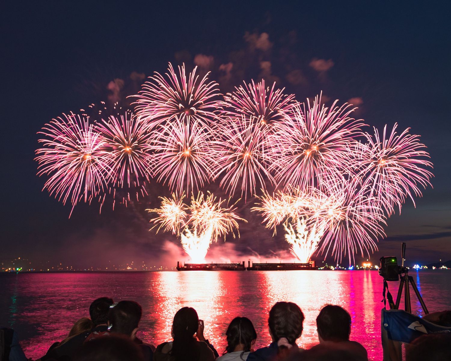 Long-exposure streaks of golden fireworks bursting above the ocean on English Bay, Vancouver