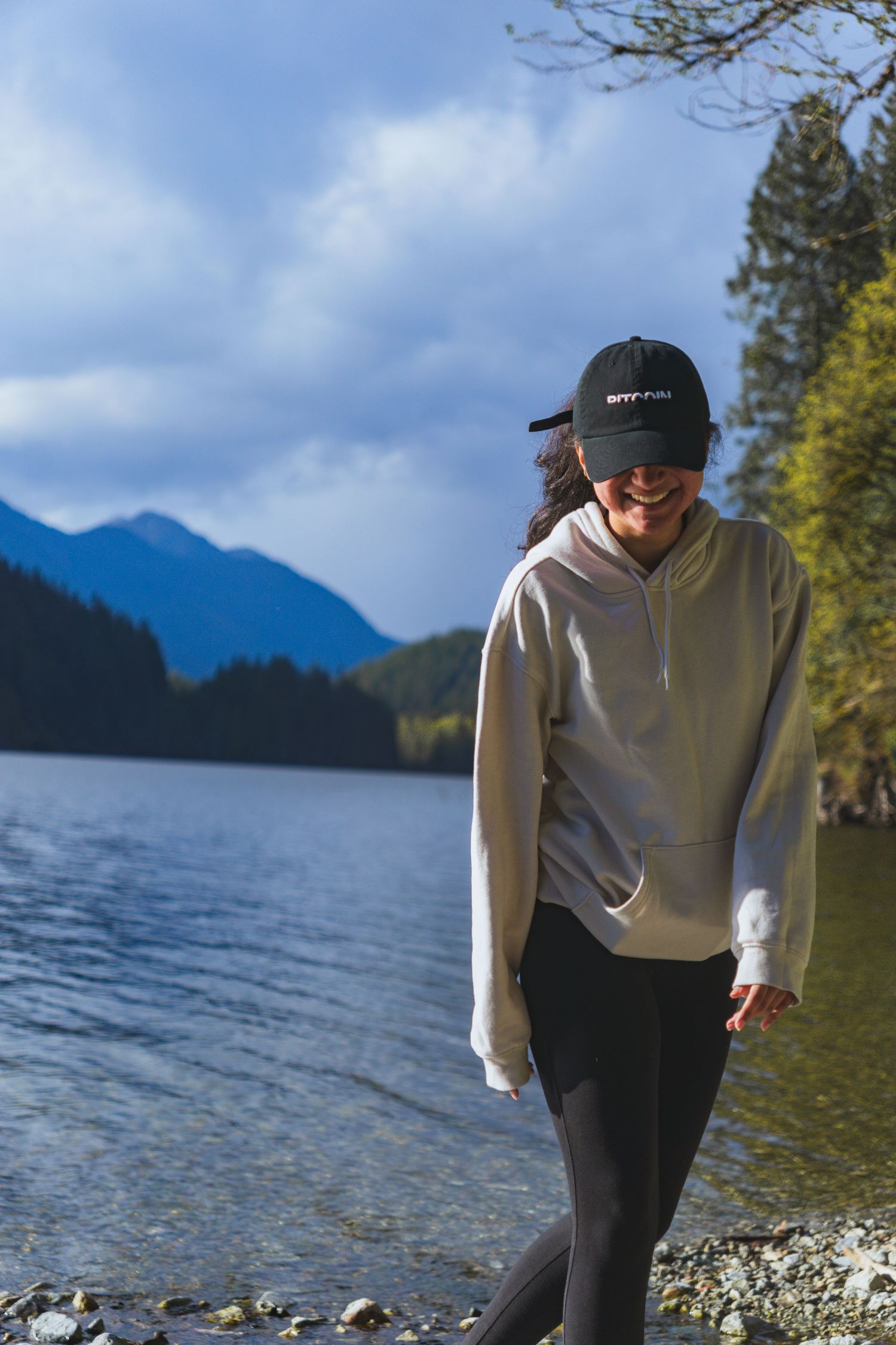 Women candidly posing with a buntzen lake background and mountains in a hoodie on a sunny afternoon in Buntzen lake, Vancouver