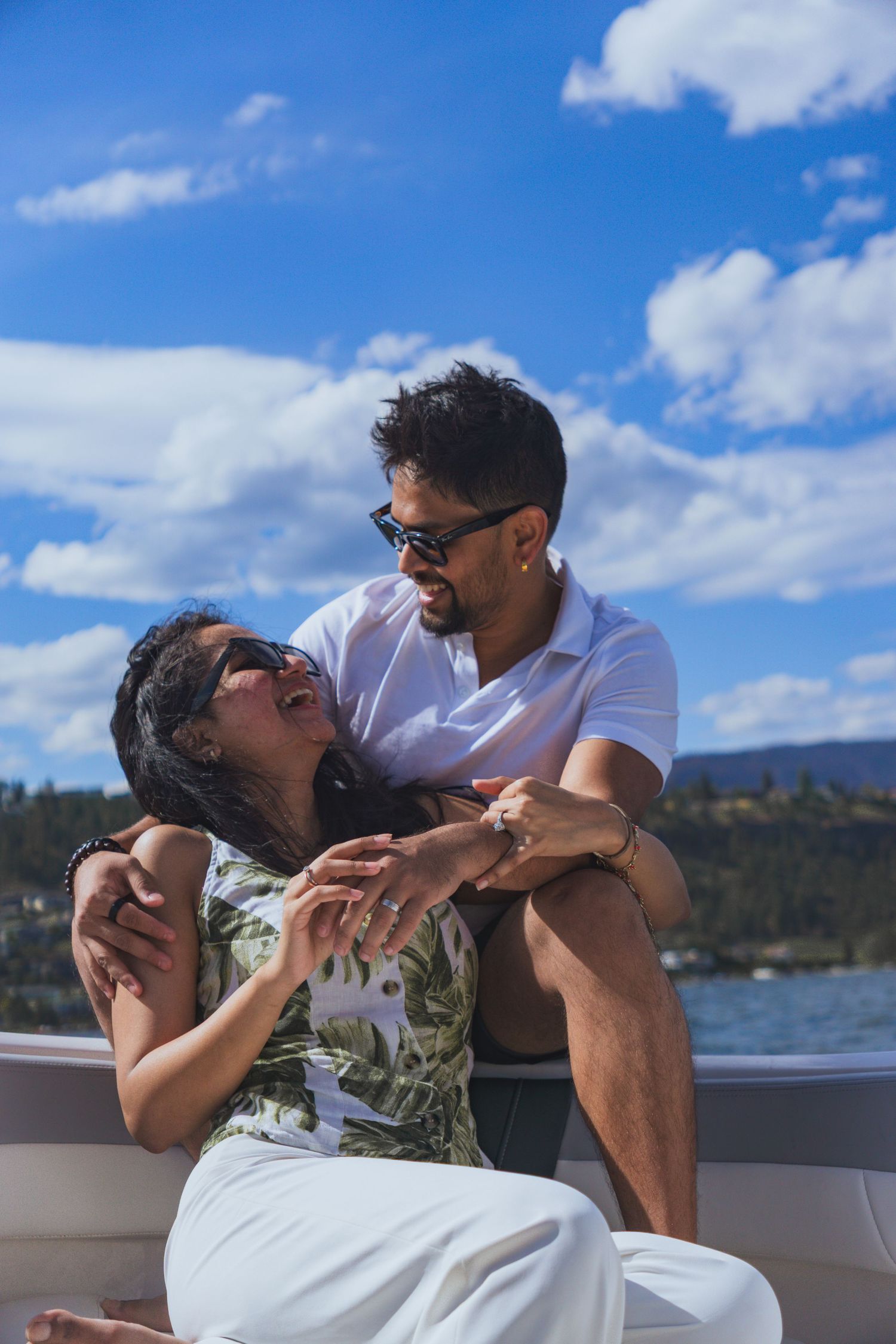 Couples candidly laughing through the boat ride with sunlight on a summer day in Kelowna, Canada