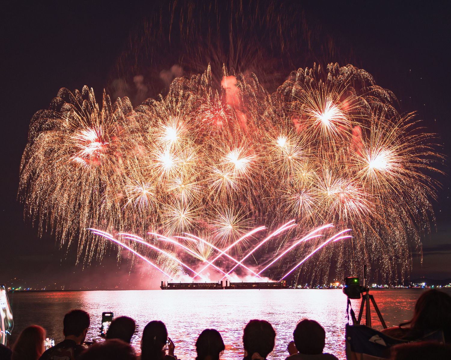 Vibrant red and blue fireworks against deep navy sky at English Bay