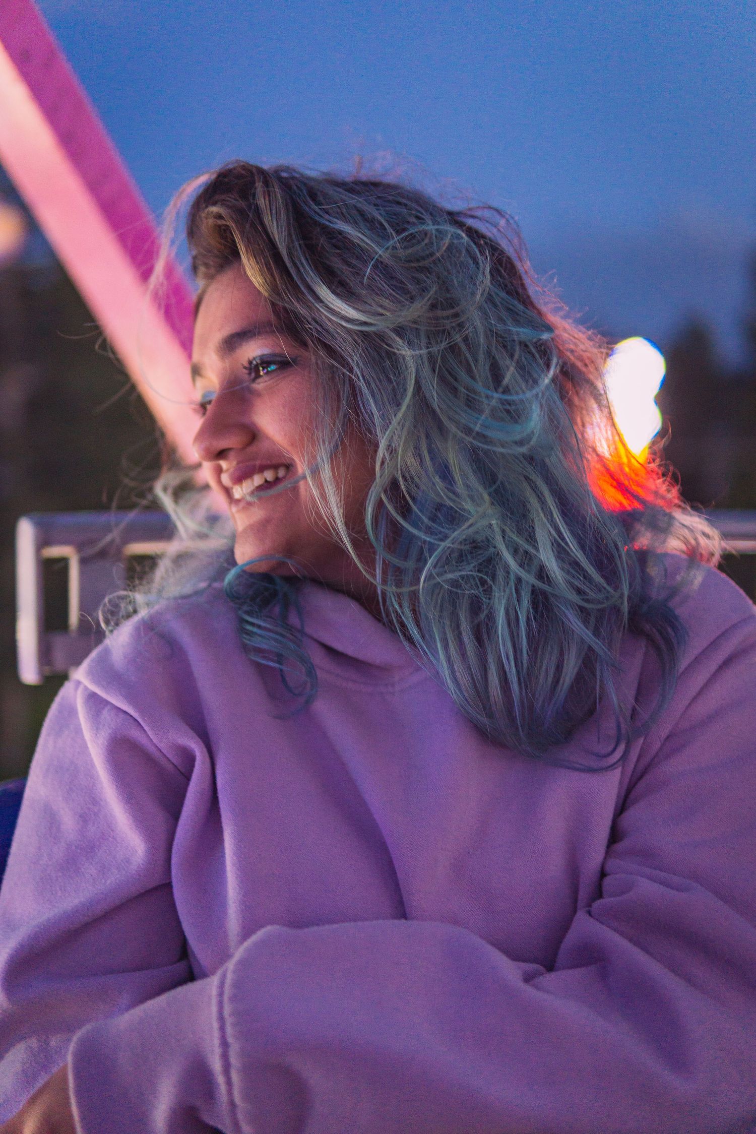 Joyful nighttime shot of woman at fair, surrounded by energy and color in Victoria, Canada