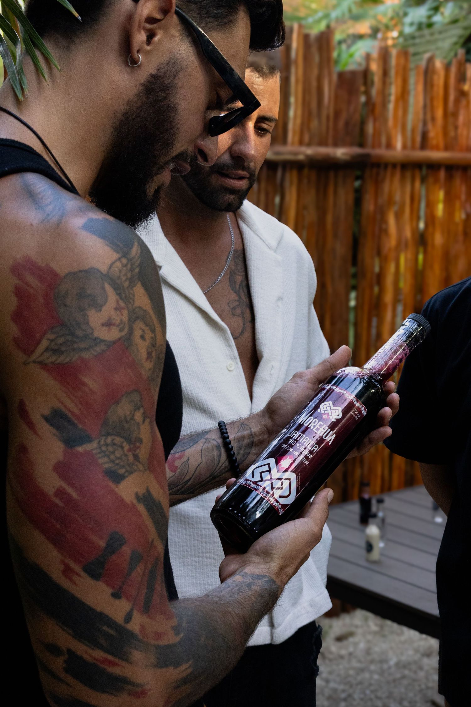 Fotografia de producto dos hombres en plano corto observando una botella de mezcal que uno de ellos sostiene con la mano