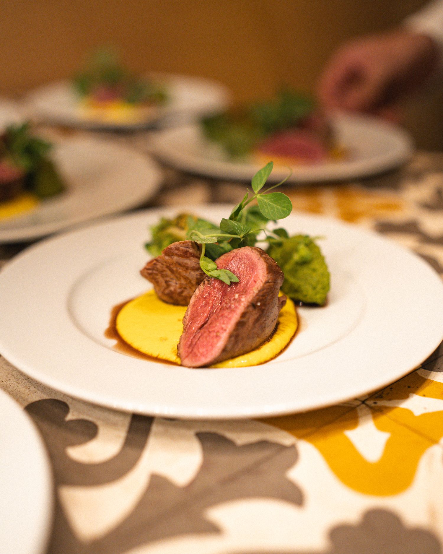 A perfectly cooked medium-rare steak served on a white plate with fresh herbs and vibrant sauces.