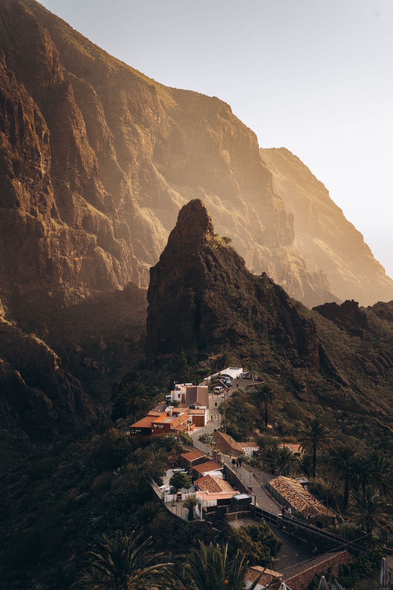 Sunset view of coastal mountains and buildings in Tenerife with dramatic cliff formations.