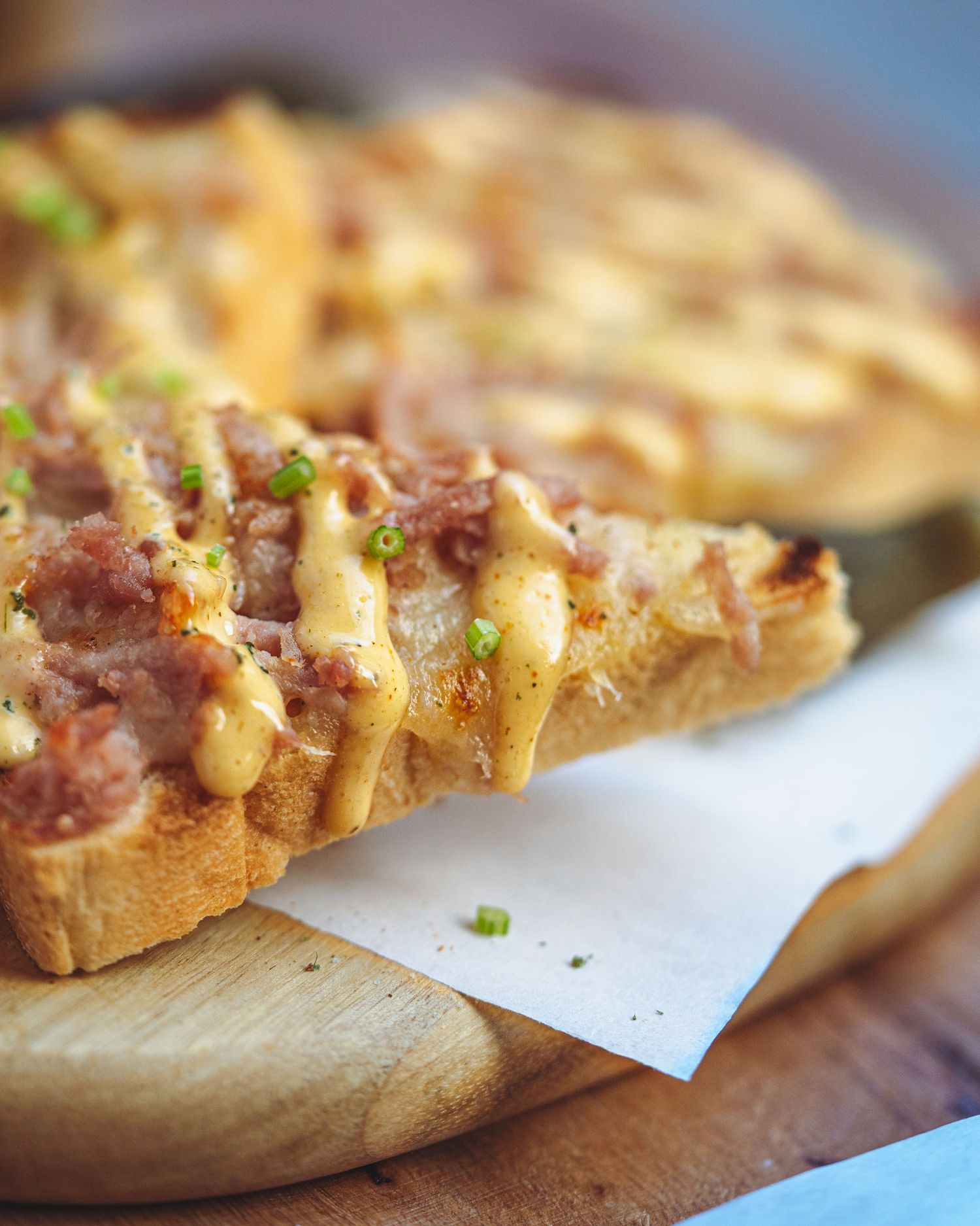 Close-up of toasted bread topped with melted cheese and meat garnished with fresh herbs.