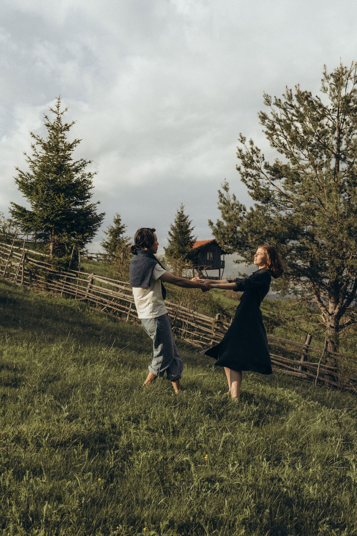 Friends enjoying a playful moment running up a green hillside with evergreen trees in the background.