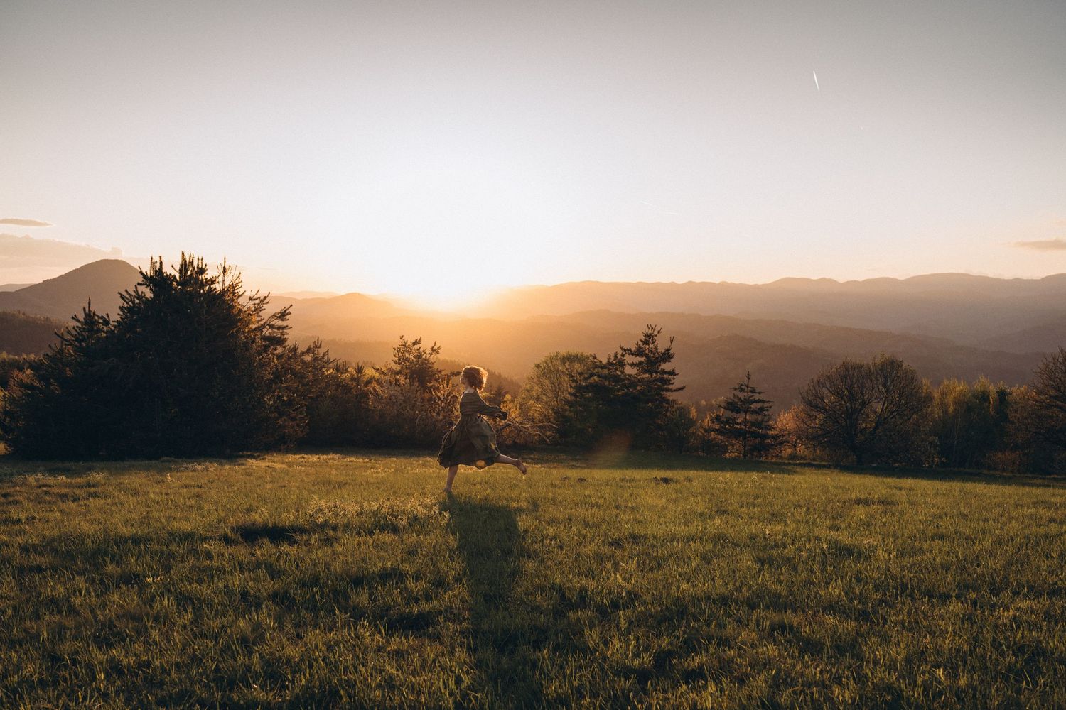 A lone figure stands silhouetted against a dramatic mountain sunset.