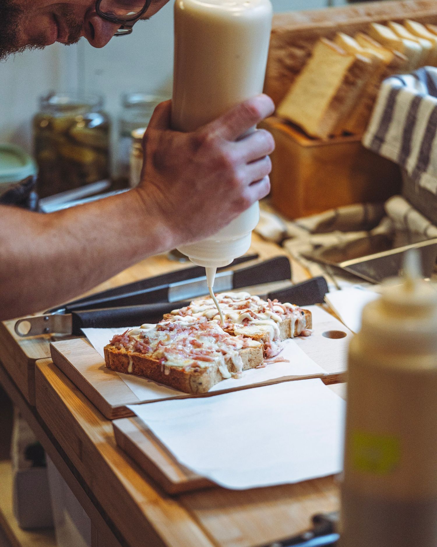 Baker decorating pastries on wooden cutting board in warm lighting.