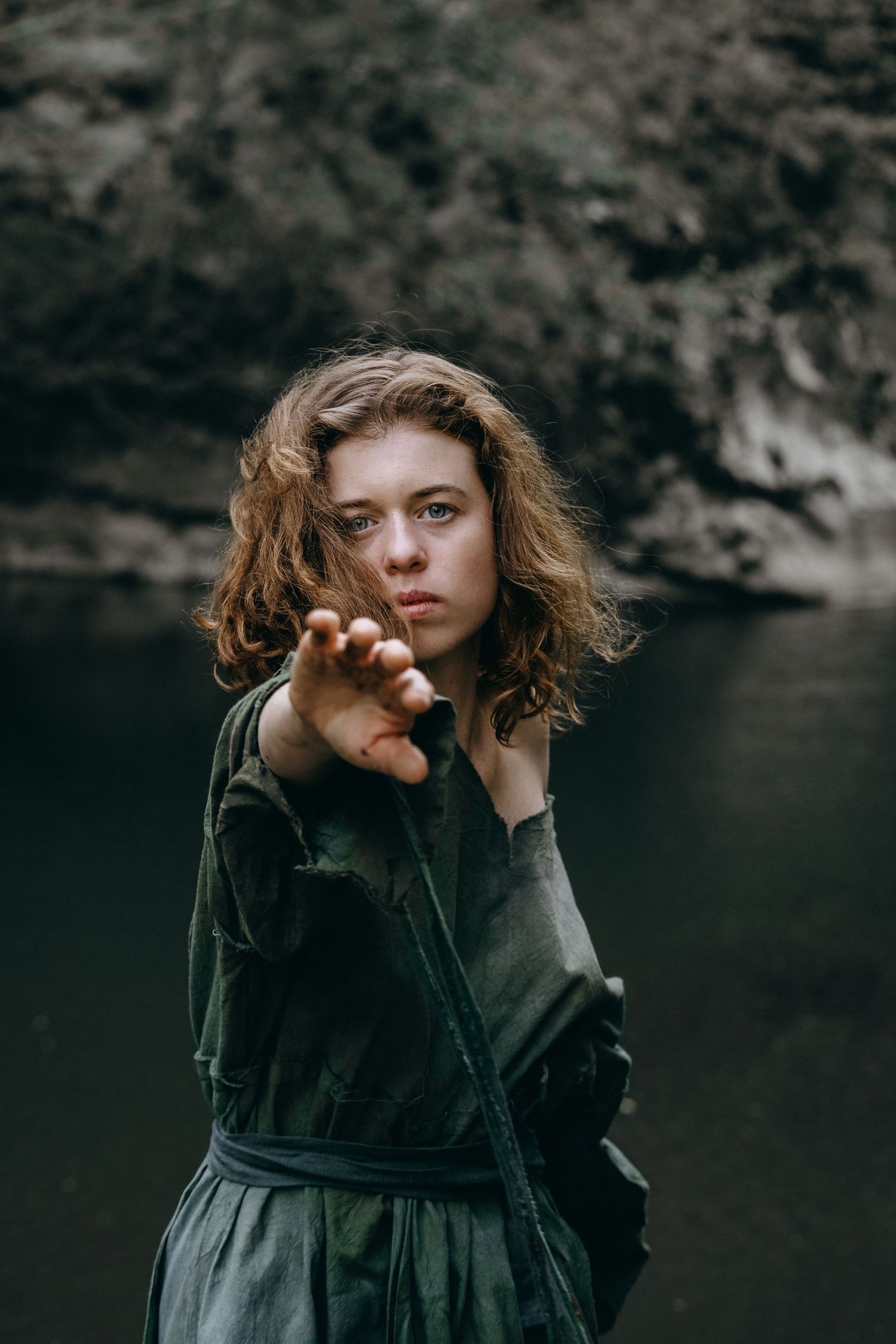 Moody portrait against dark water background with dramatic artistic pose.