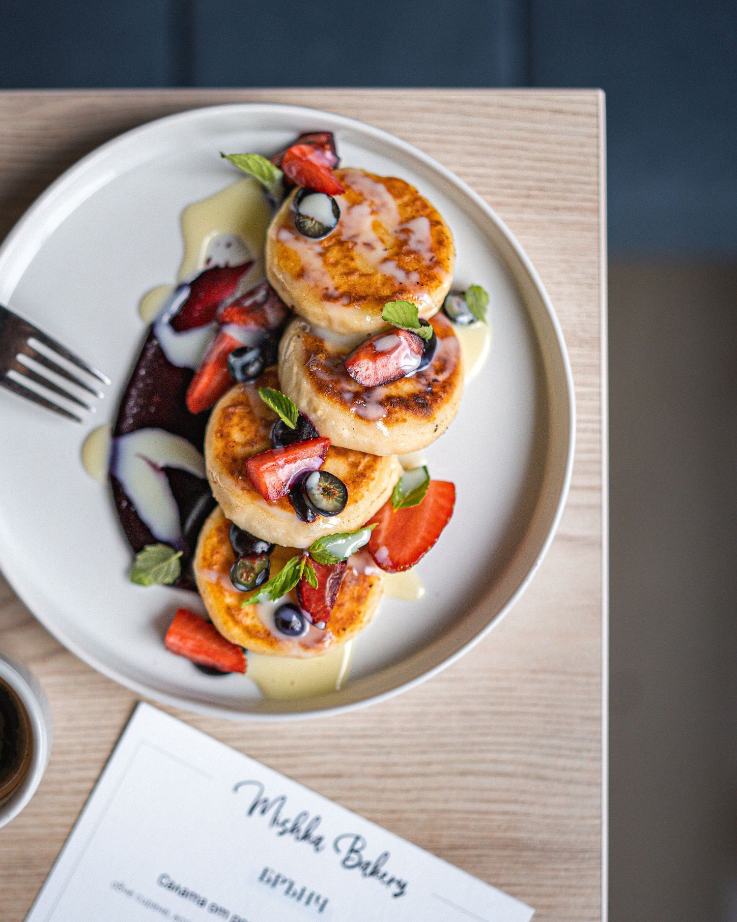 Seared scallops garnished with fresh strawberries and herbs on a white plate.