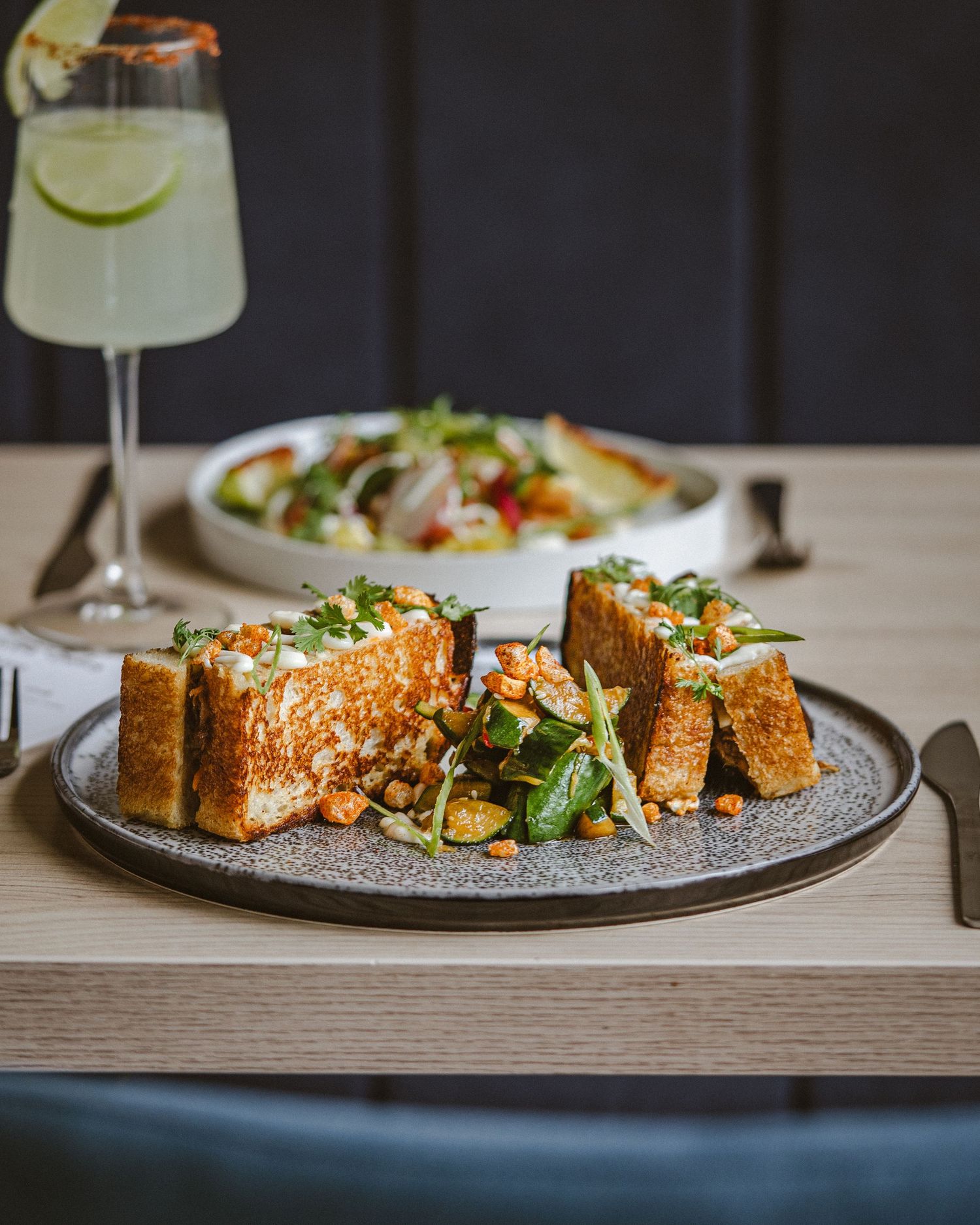 Artfully arranged toasted bread slices with toppings served on a textured gray plate.