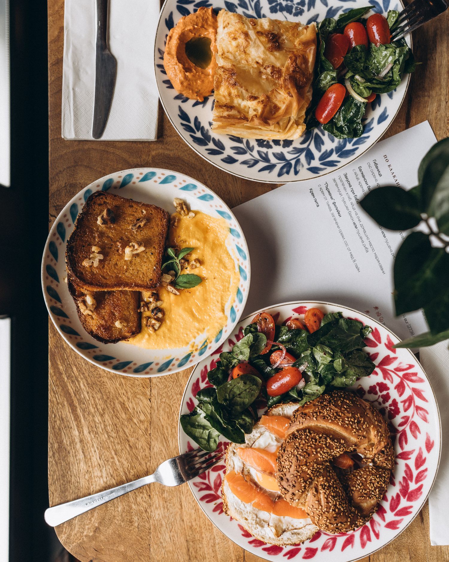 Rustic plates of golden bagels with cream cheese, smoked salmon, and fresh greens arranged on a wooden surface.