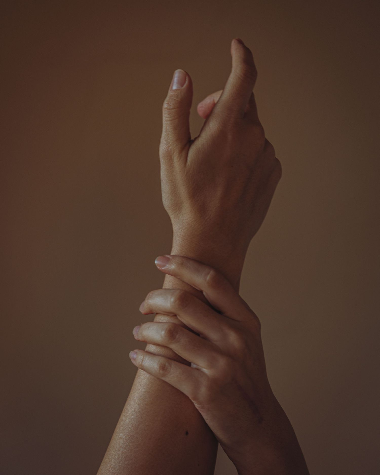 Close-up of hands reaching and intertwining against a dark moody background.