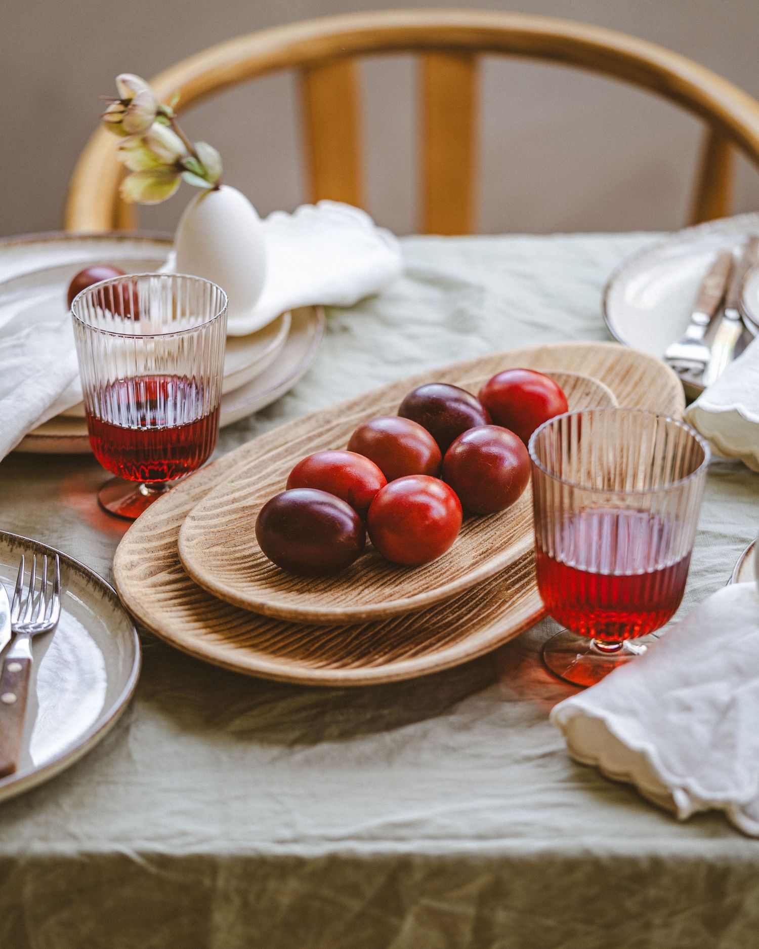 Rustic table setting with red wine glasses and fresh plums on wooden serving plates.