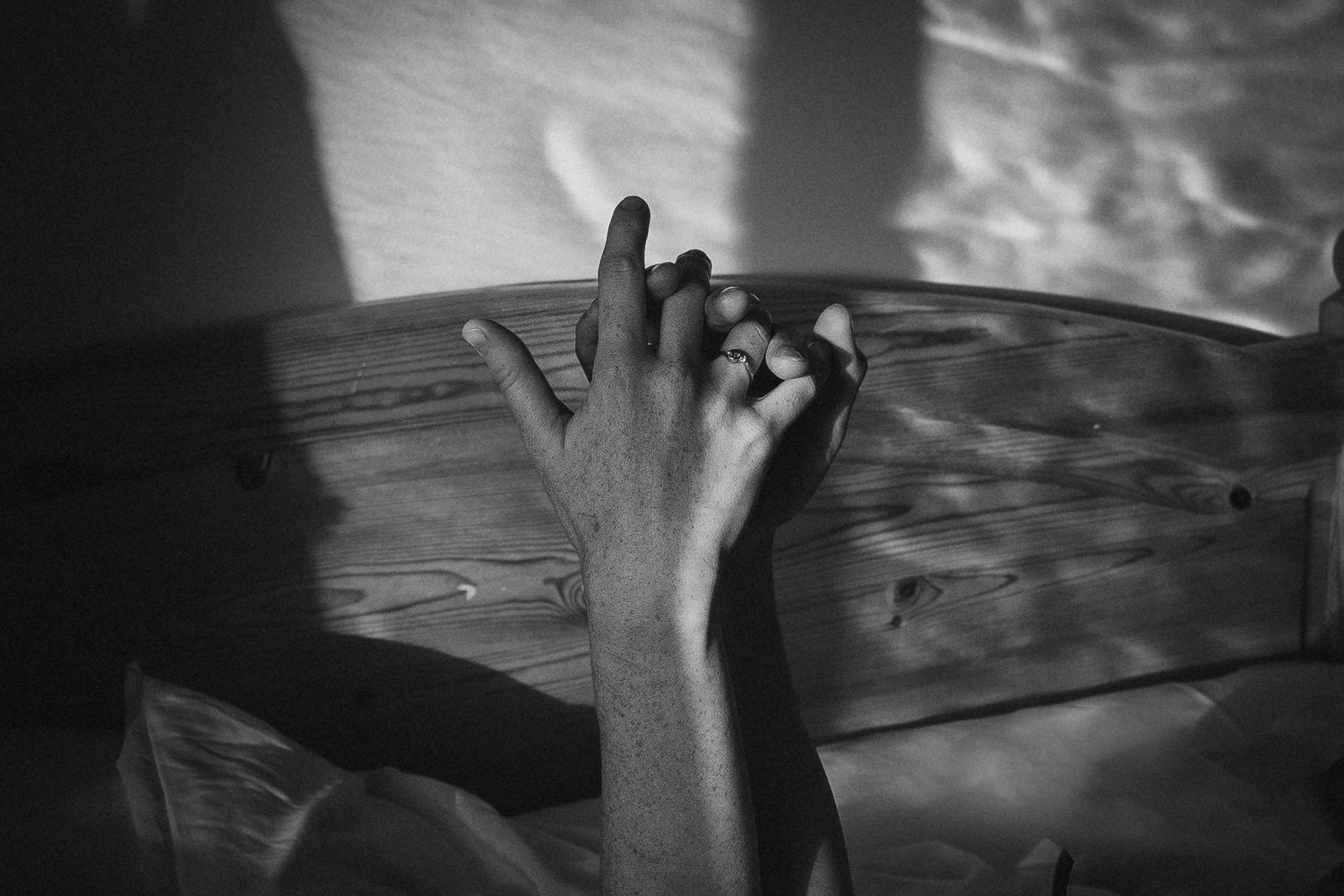 Silhouetted hands reaching up against a dramatic cloudy sky at sunset.