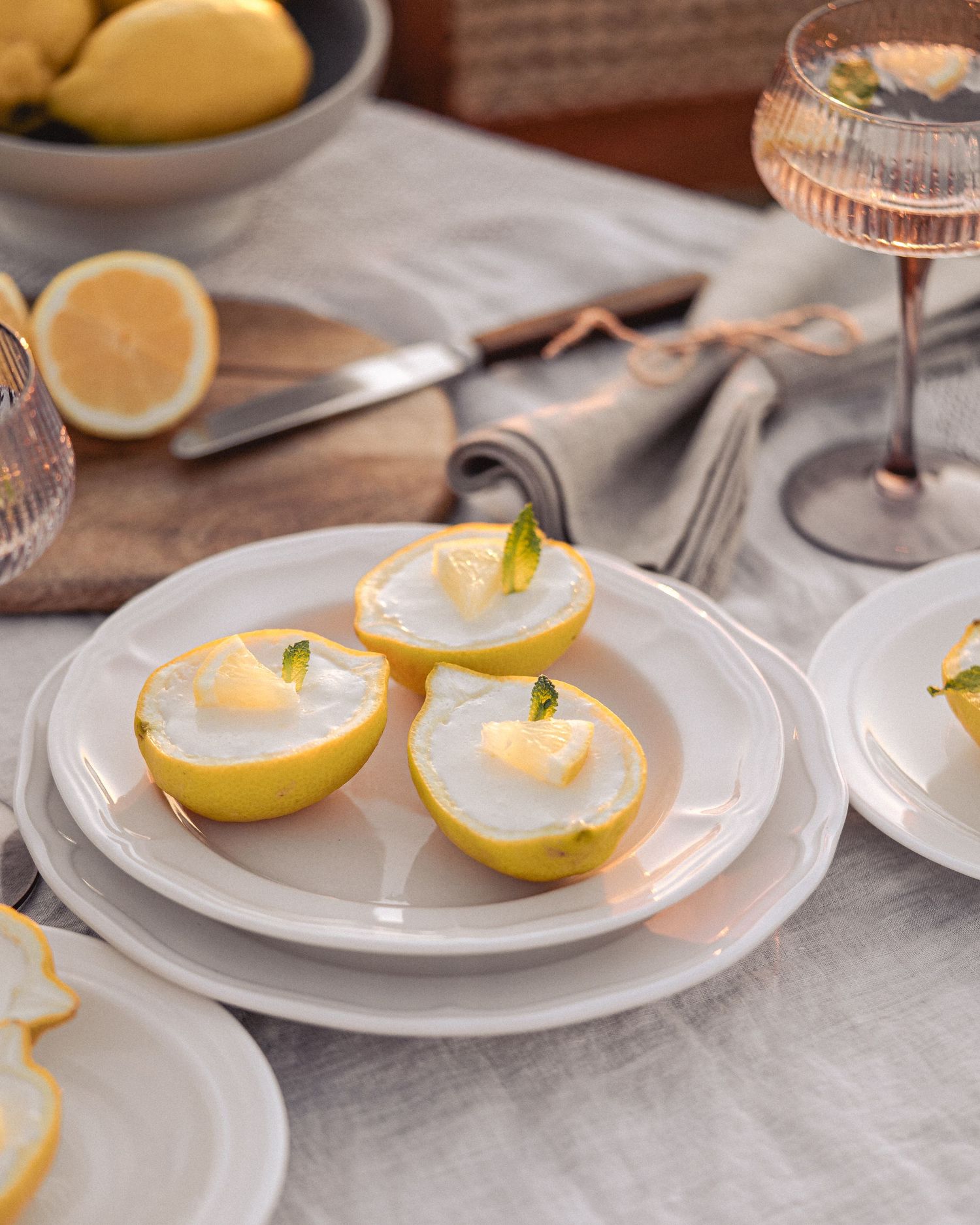 White plates displaying lemon desserts with whipped cream and mint garnish on a light surface.