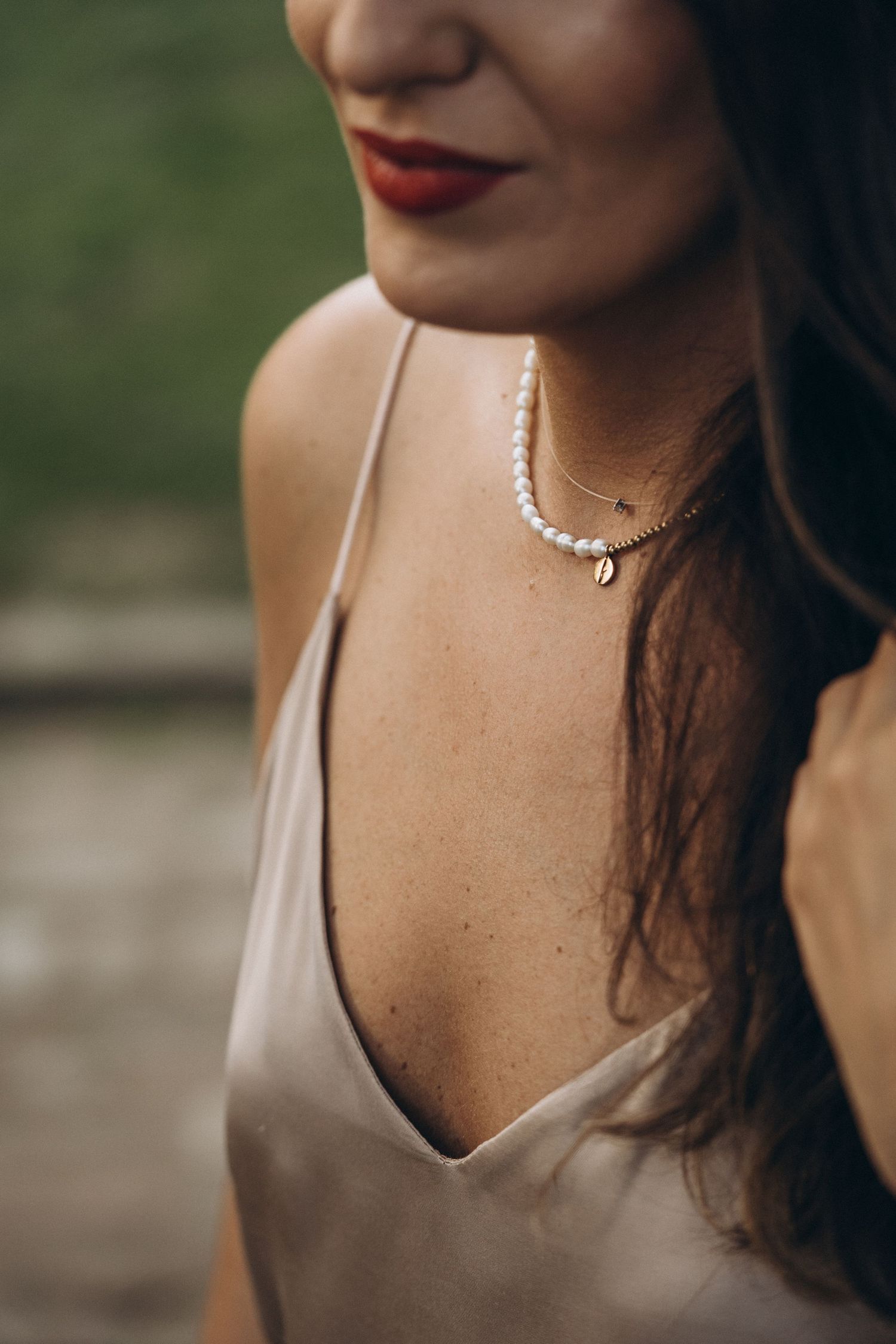 Close-up shot showing a delicate silver necklace against skin in natural lighting.
