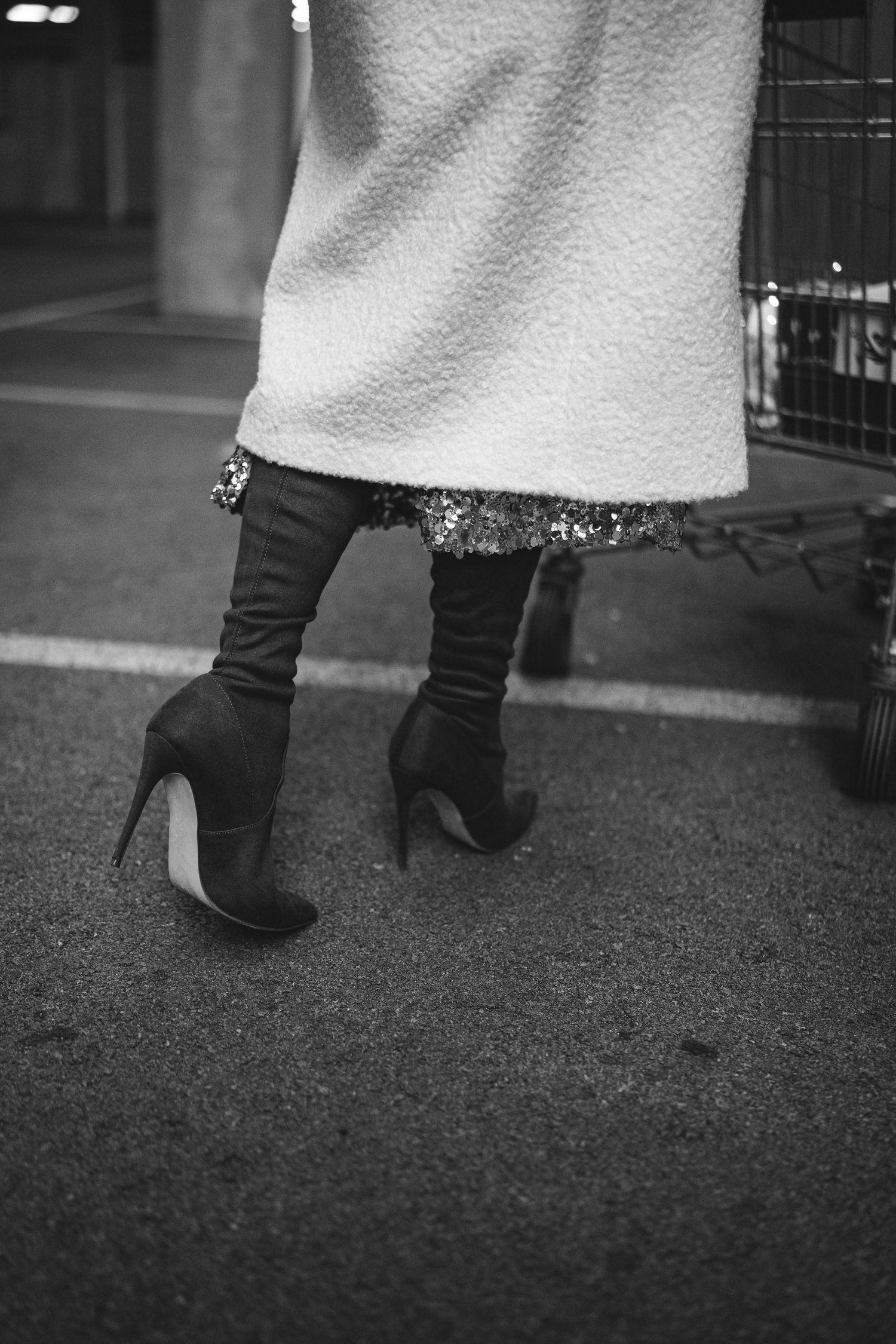 Close-up black and white photo of boots and a white dress against dark pavement.