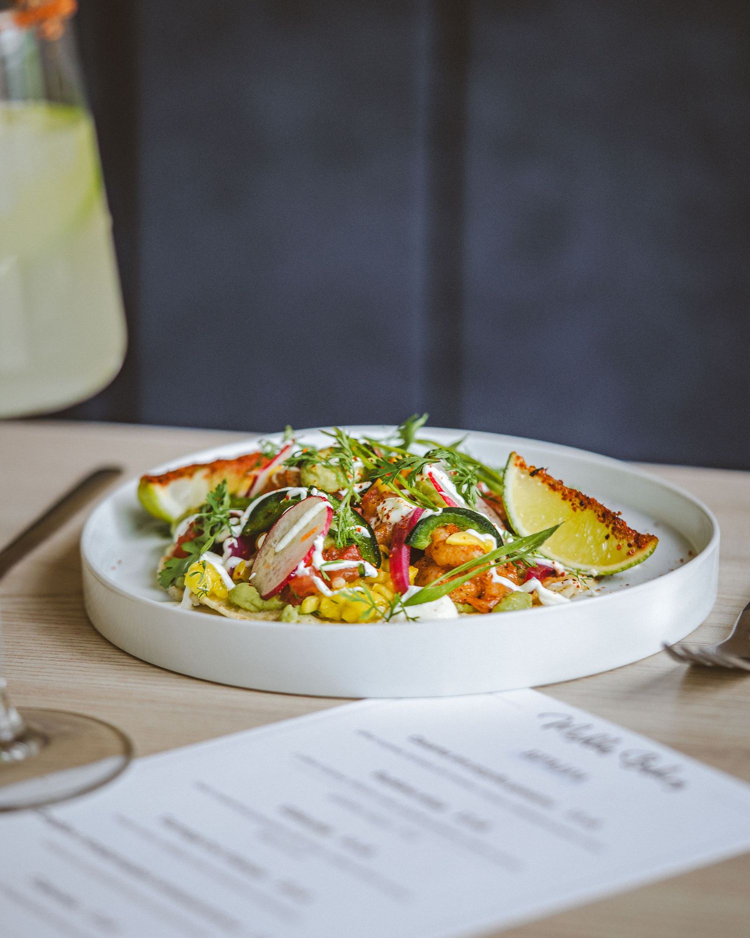 Elegantly plated seafood dish with fresh greens and colorful garnishes on a white ceramic plate.