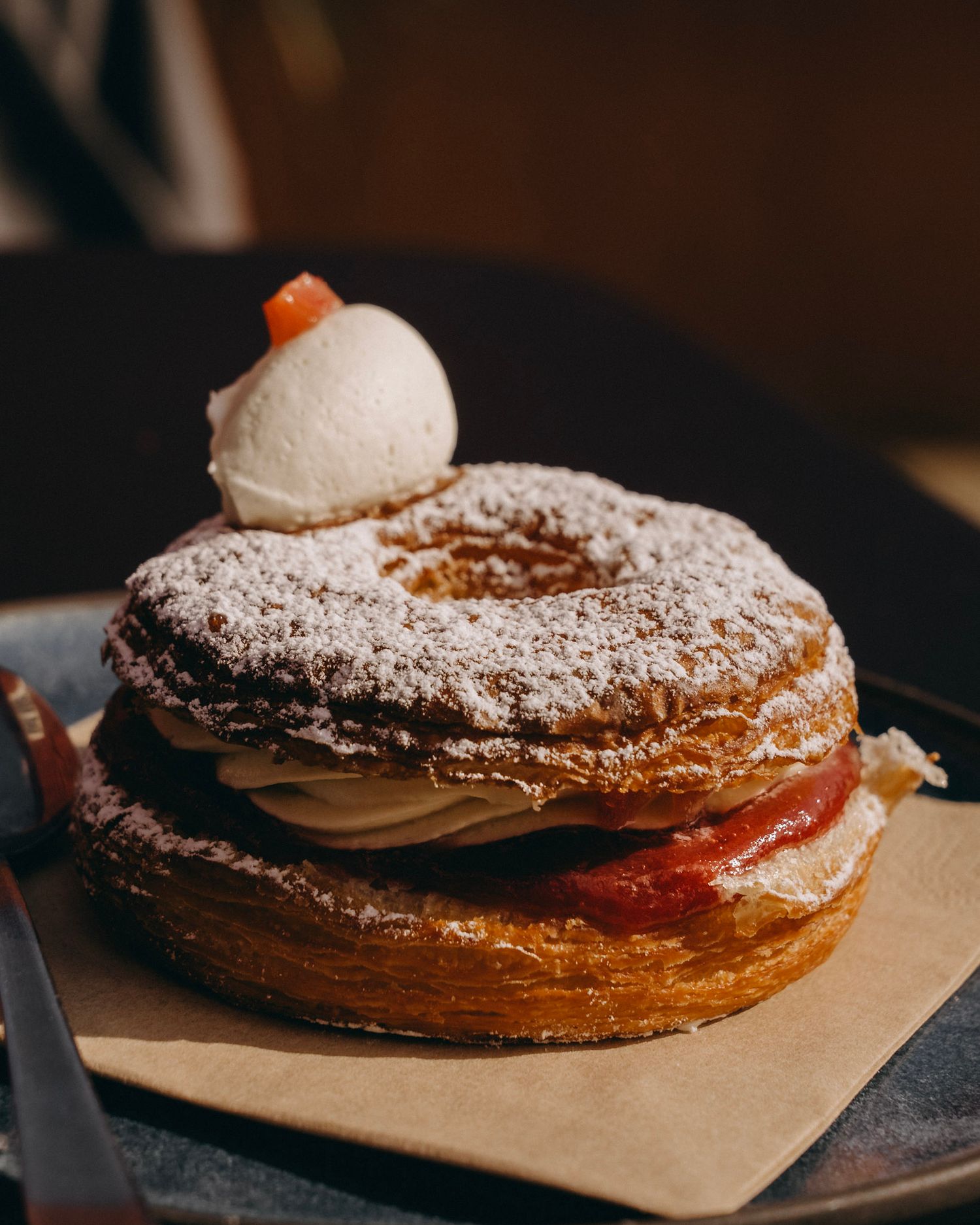Close-up of a layered pastry dusted with powdered sugar on brown paper.