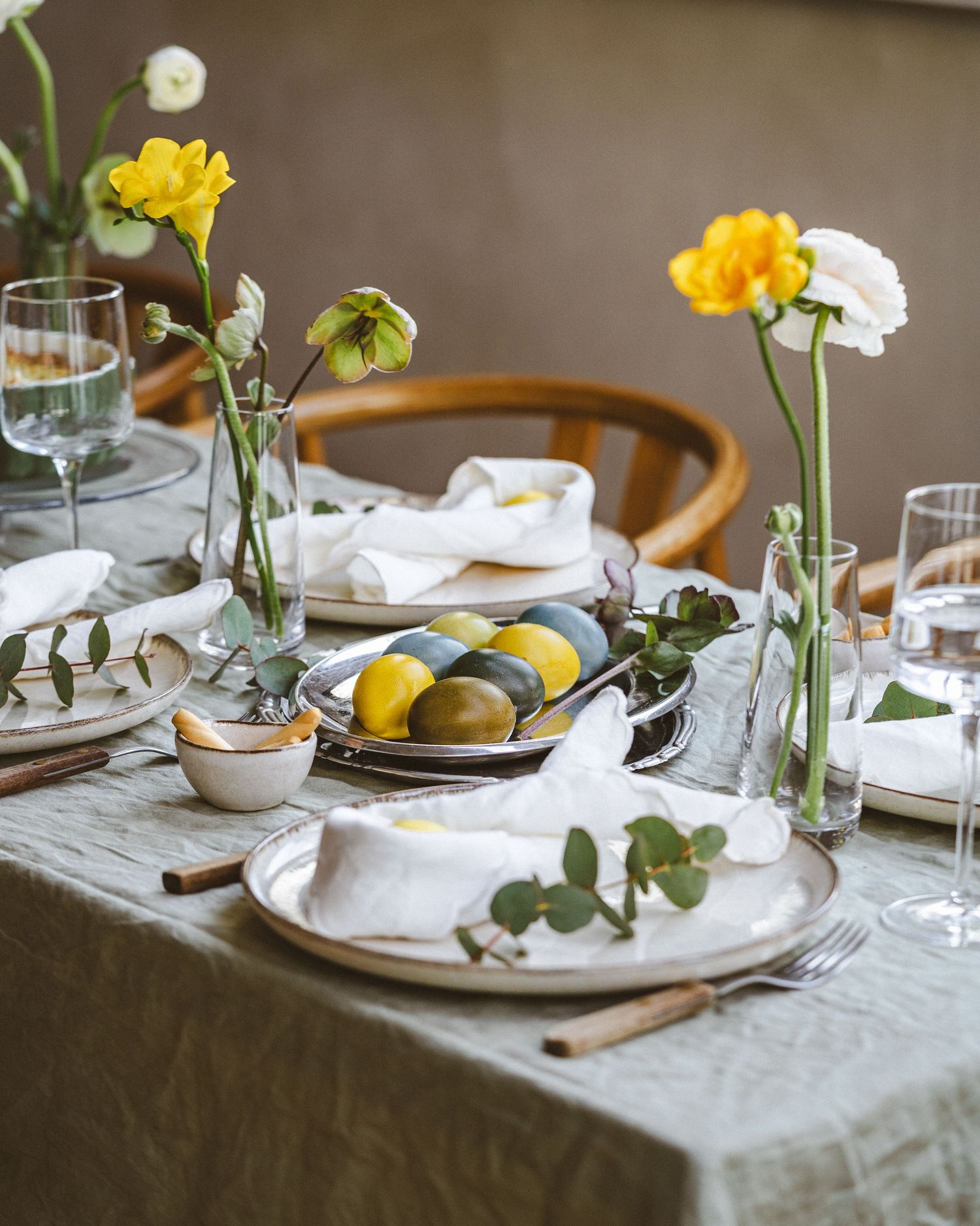 Elegant spring table setting with yellow flowers, lemons, and white table linens.
