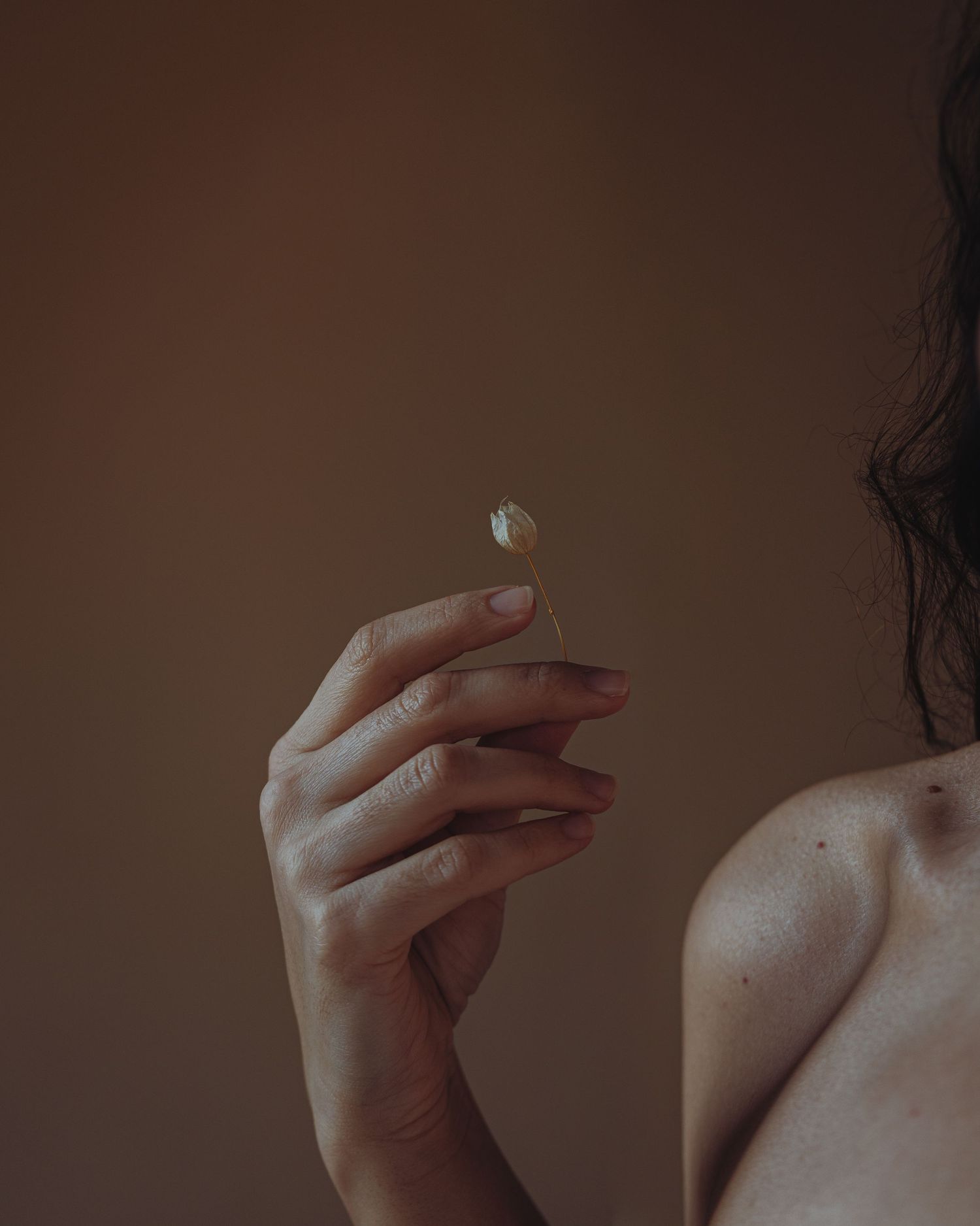 Artistic close-up of hands against dark background with dramatic lighting.