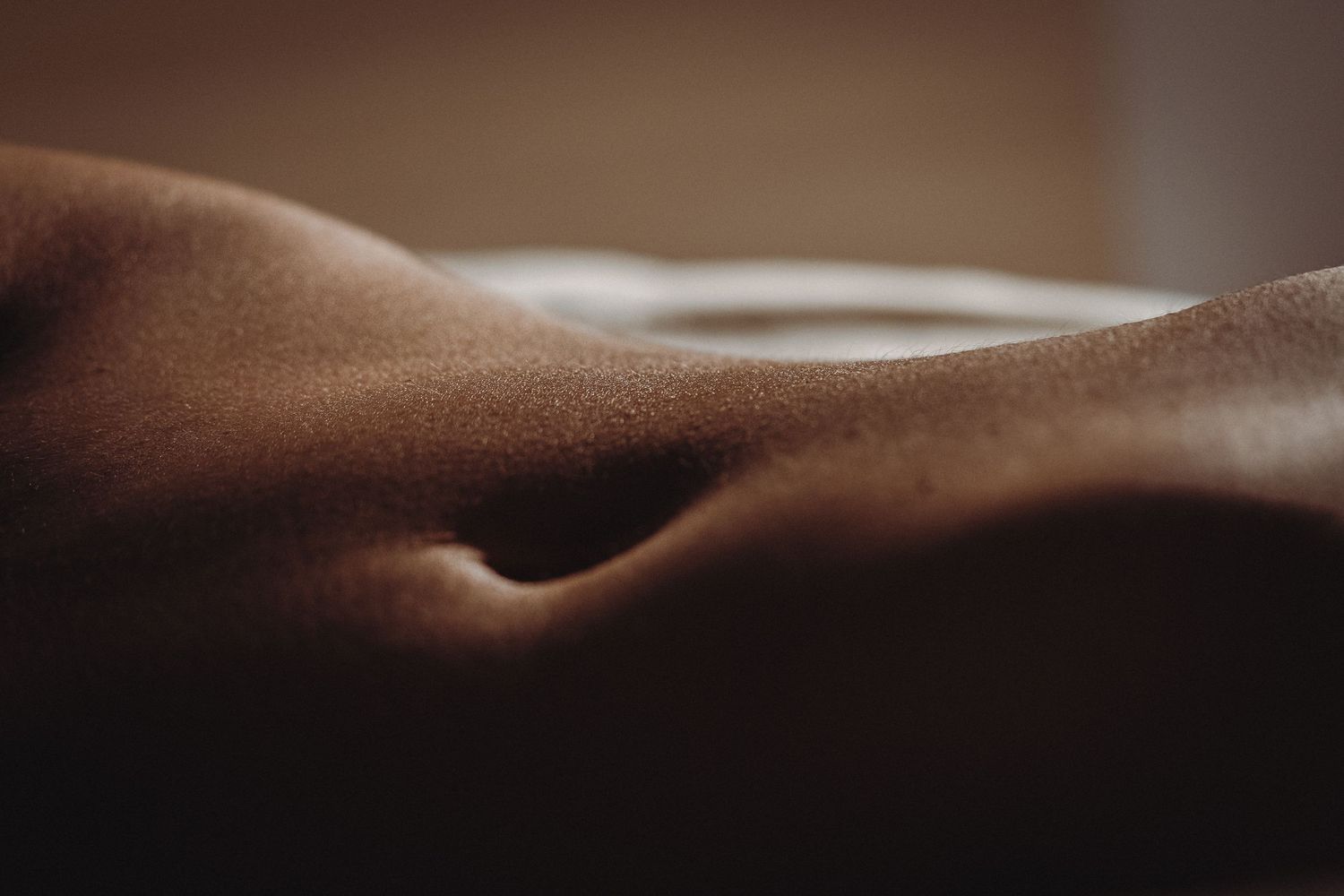 Abstract artistic photography of curved body forms in soft, shadowy lighting.