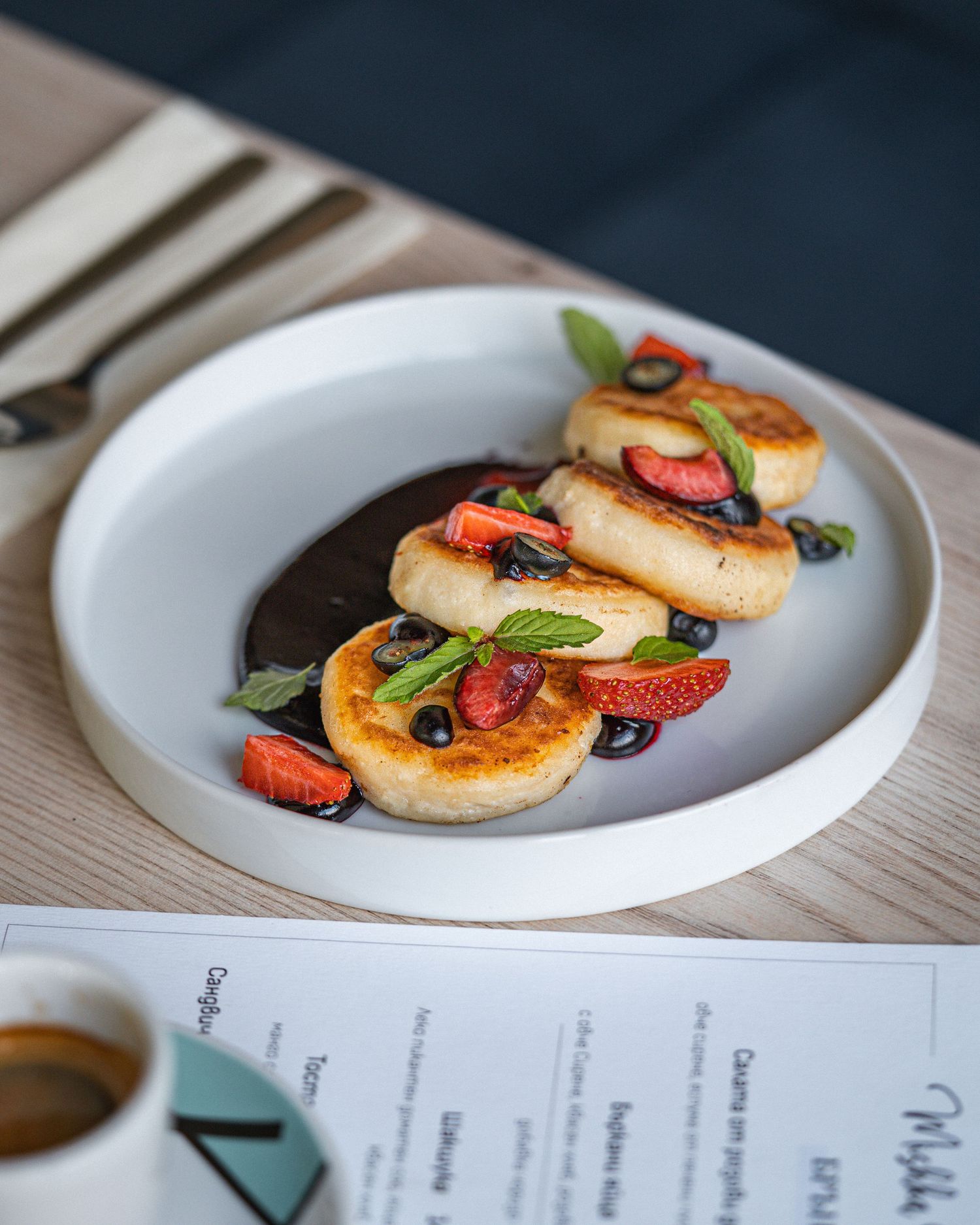 Grilled scallops with strawberries and microgreens plated on white dinnerware.