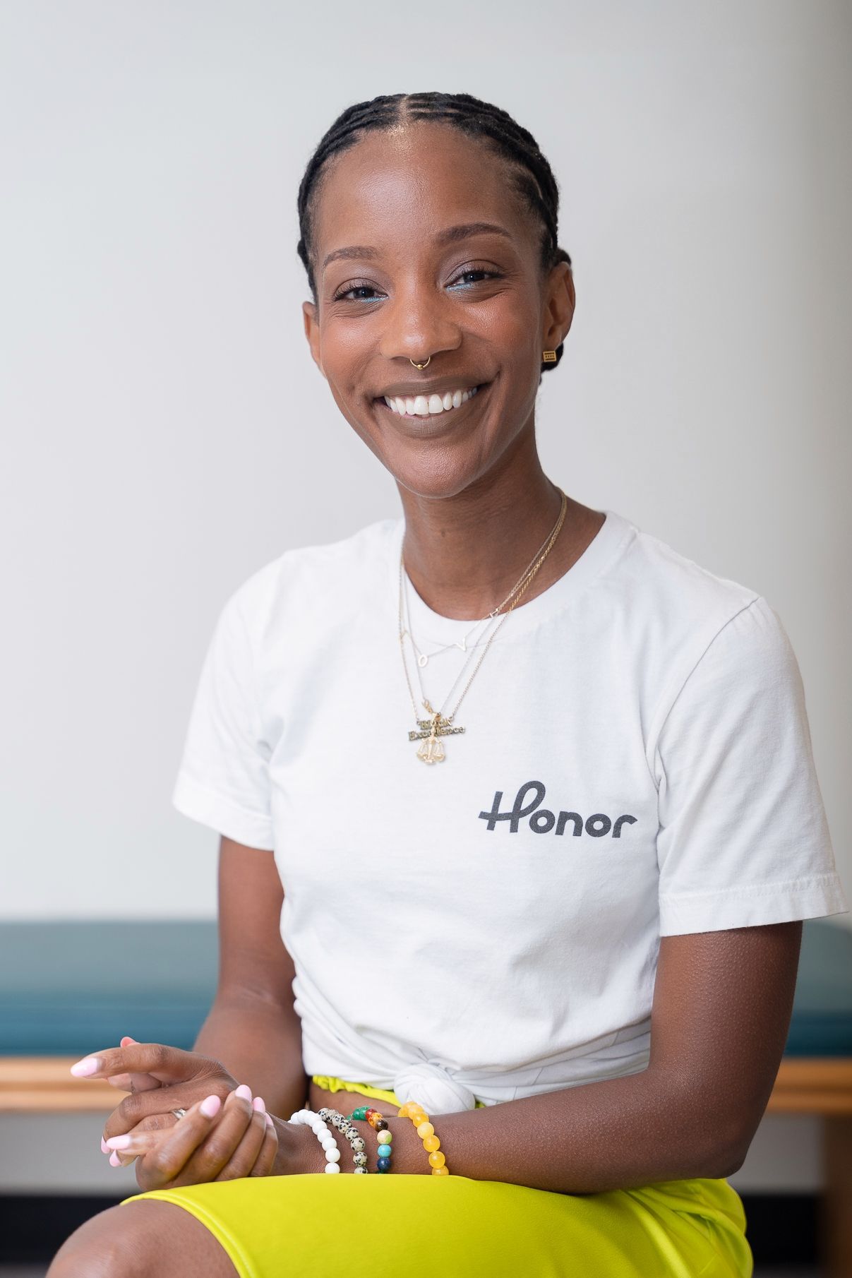 Portrait series of person in white Honor t-shirt with braided hair against light background.