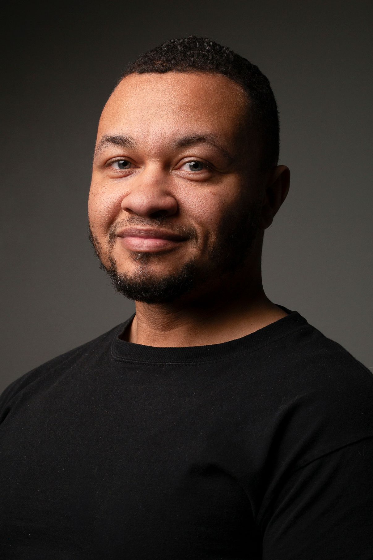 Professional headshot series of person in black shirt against dark background showing various expressions.