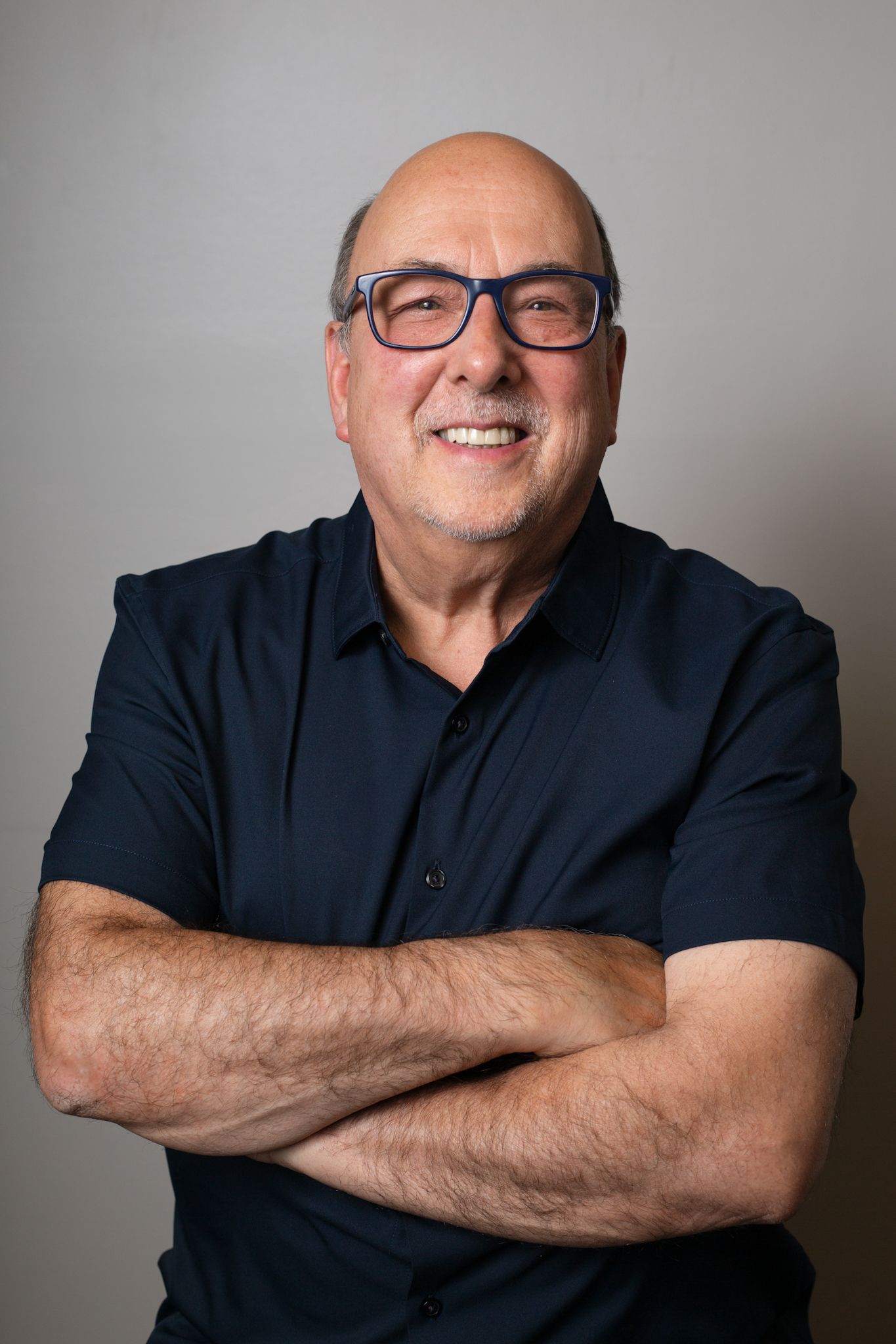 Professional studio portrait series showing warm expressions while wearing a black shirt against a light gray background.