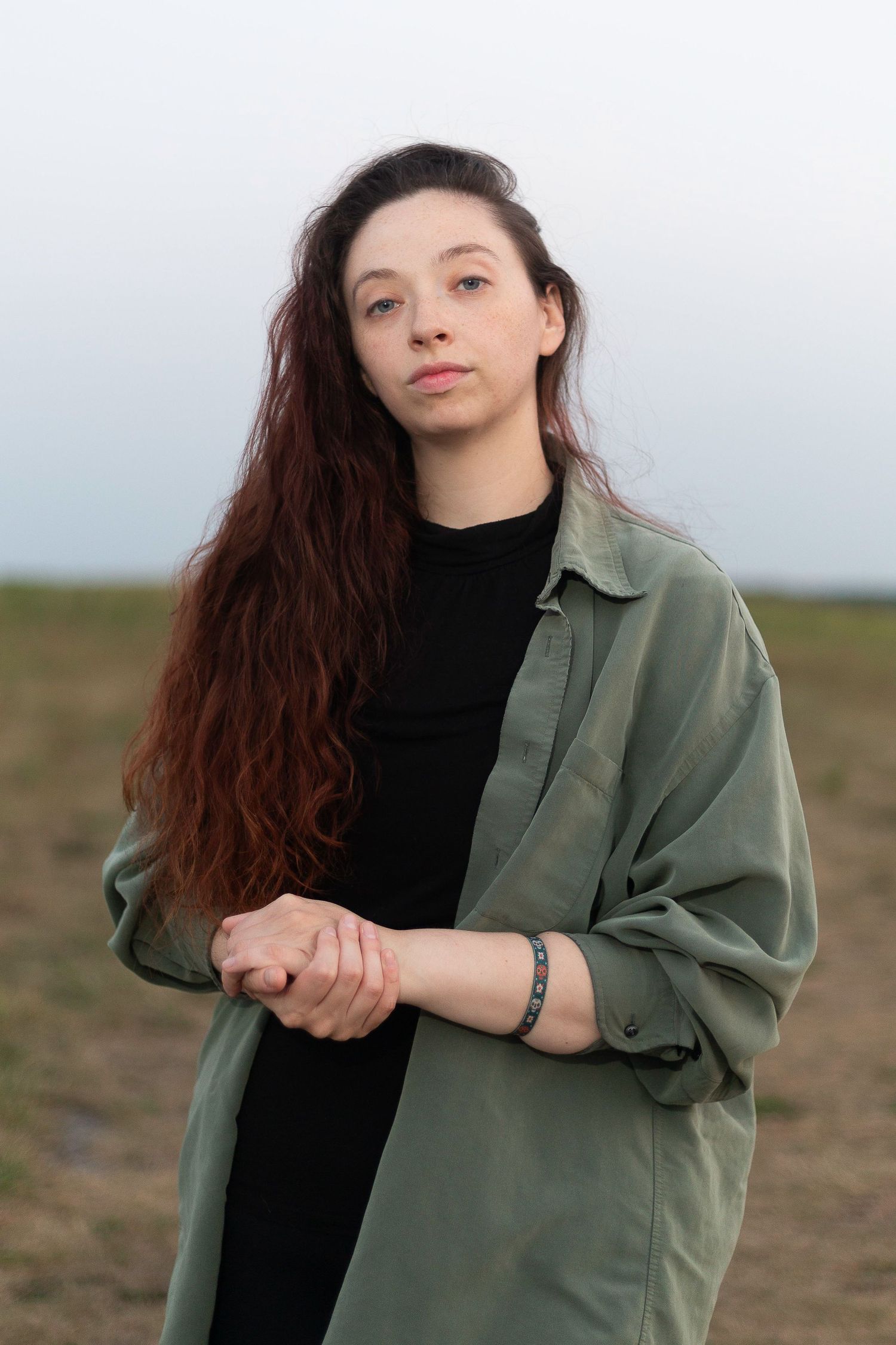 Artistic outdoor portraits with long hair and olive green jacket.