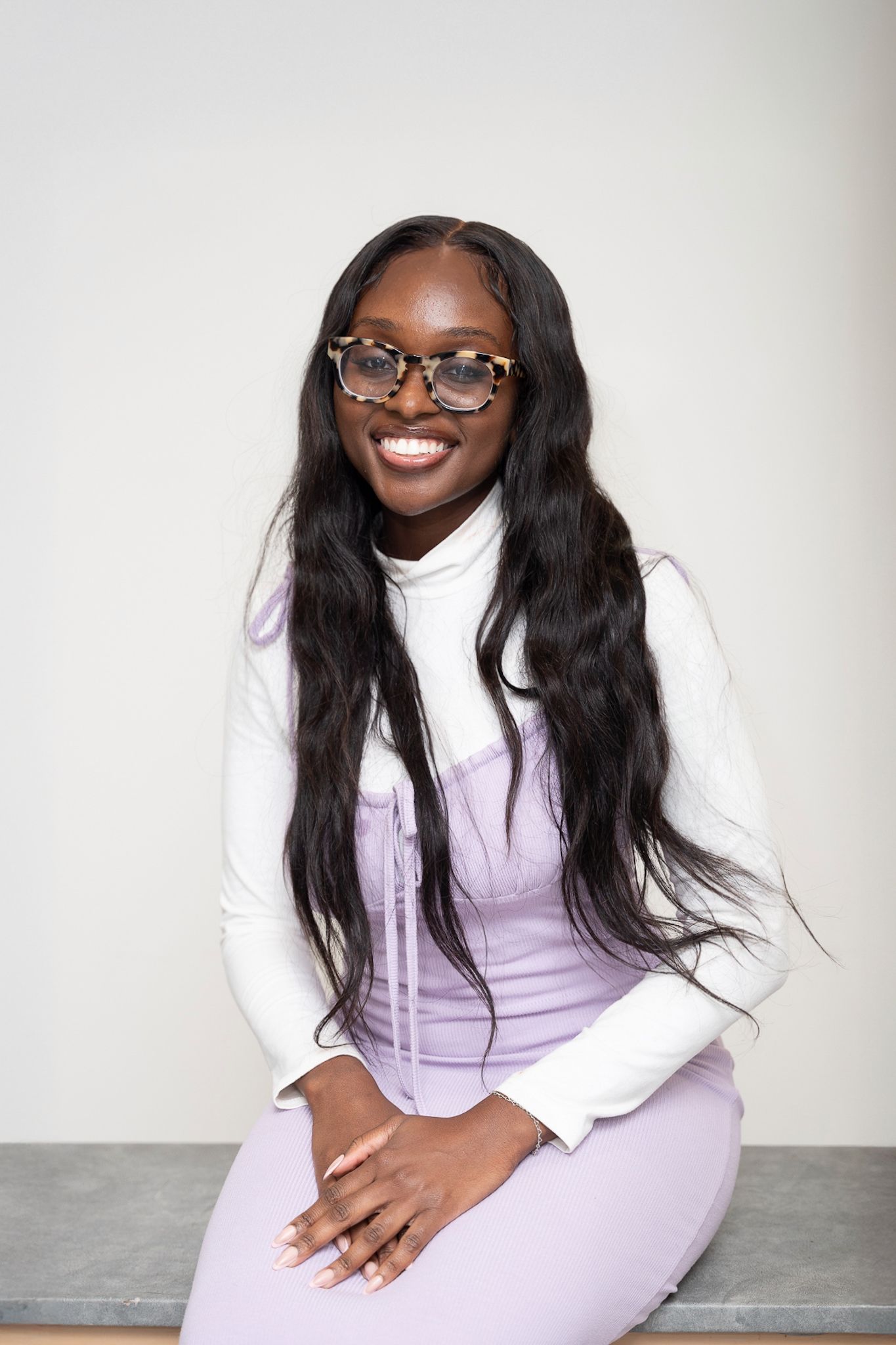 Portrait series of person in white and lavender outfit with long dark hair and glasses.