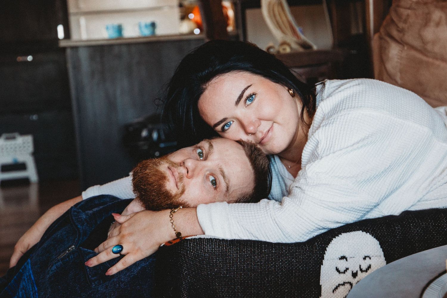 A couple relaxed at home. Faces touching and their eyes gazing out.