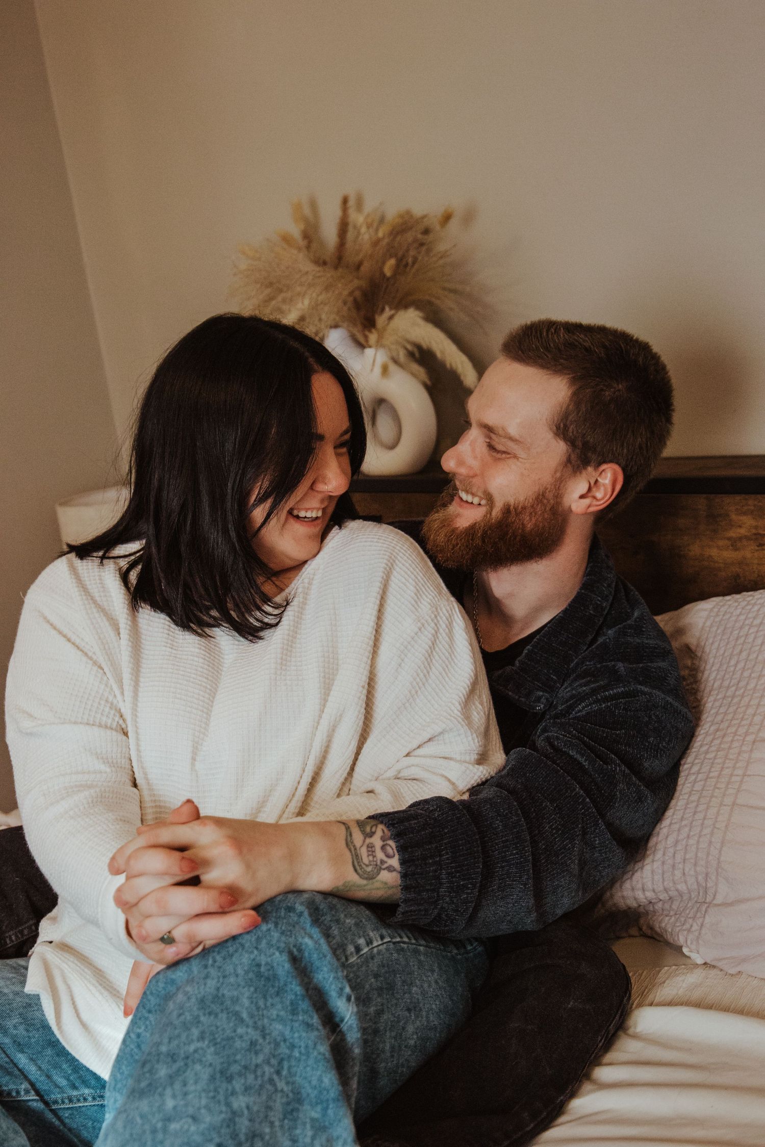 Hands folded together a couple shares a silly joke and smiles