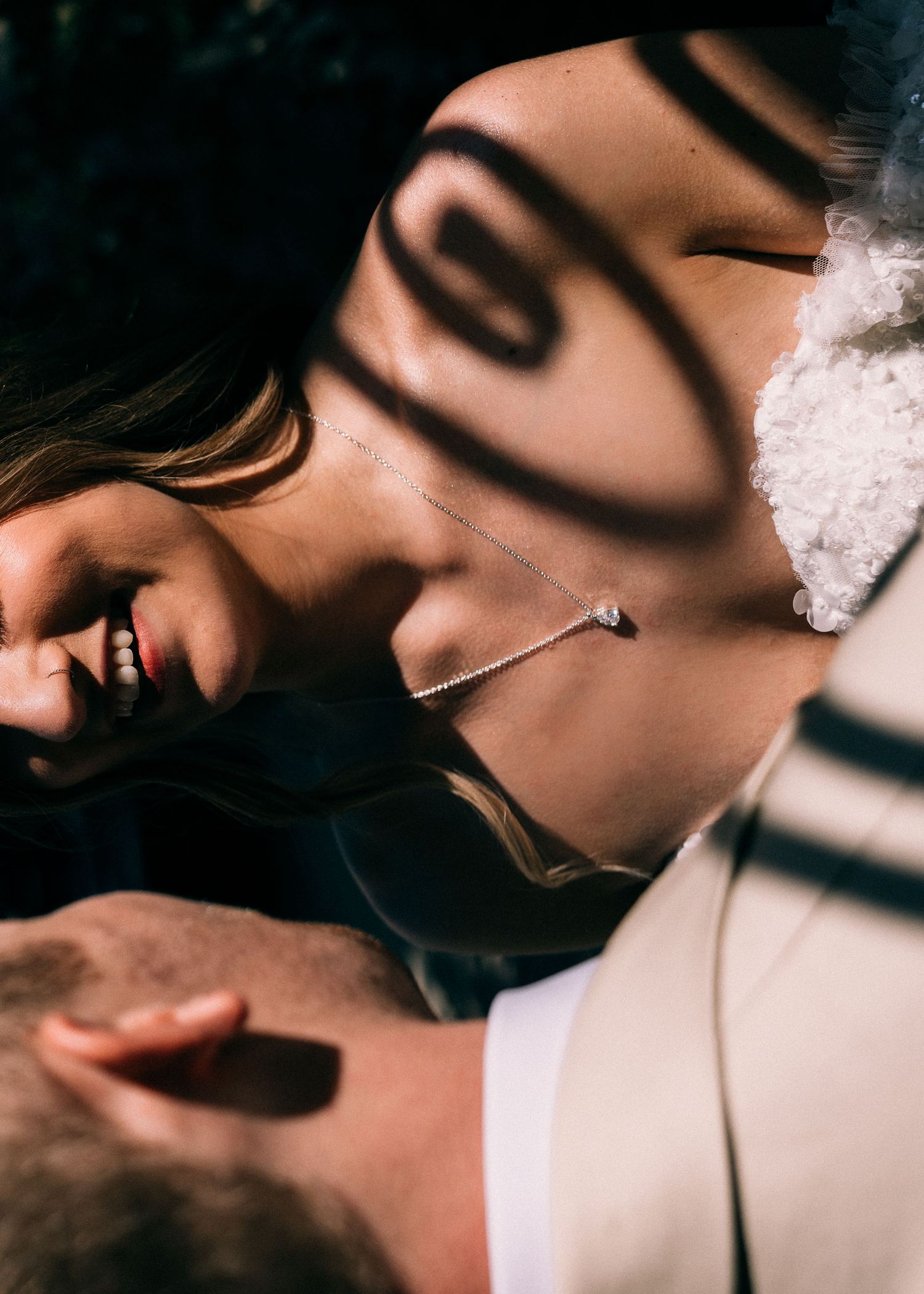 Close-up of bride and groom sharing intimate moment with dramatic shadow patterns across their faces.