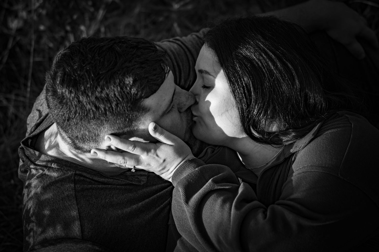 Romantic black and white photo of couple sharing a tender kiss outdoors.