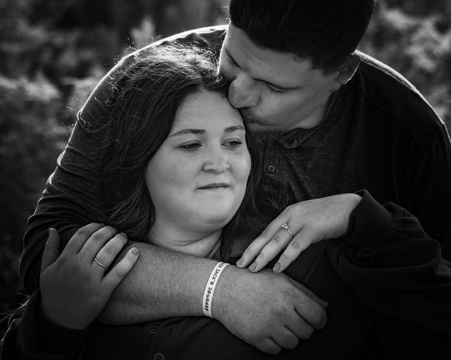 Man embracing woman from behind in a tender black and white couples portrait.