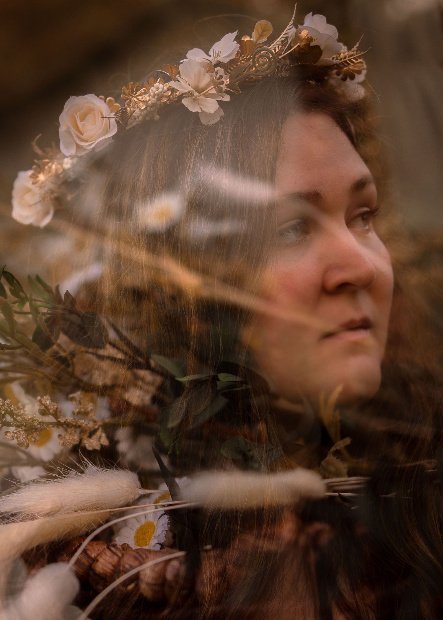 Woman wearing a floral crown with white flowers, surrounded by a dreamy double exposure of wildflowers and greenery.