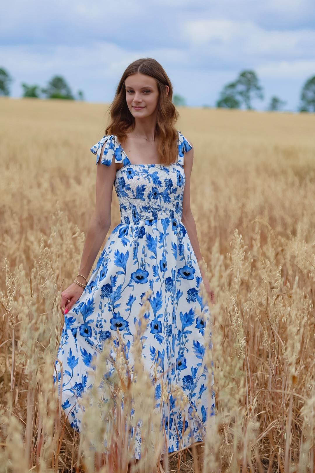 A blue and white floral dress stands out against a golden wheat field on a summer day.