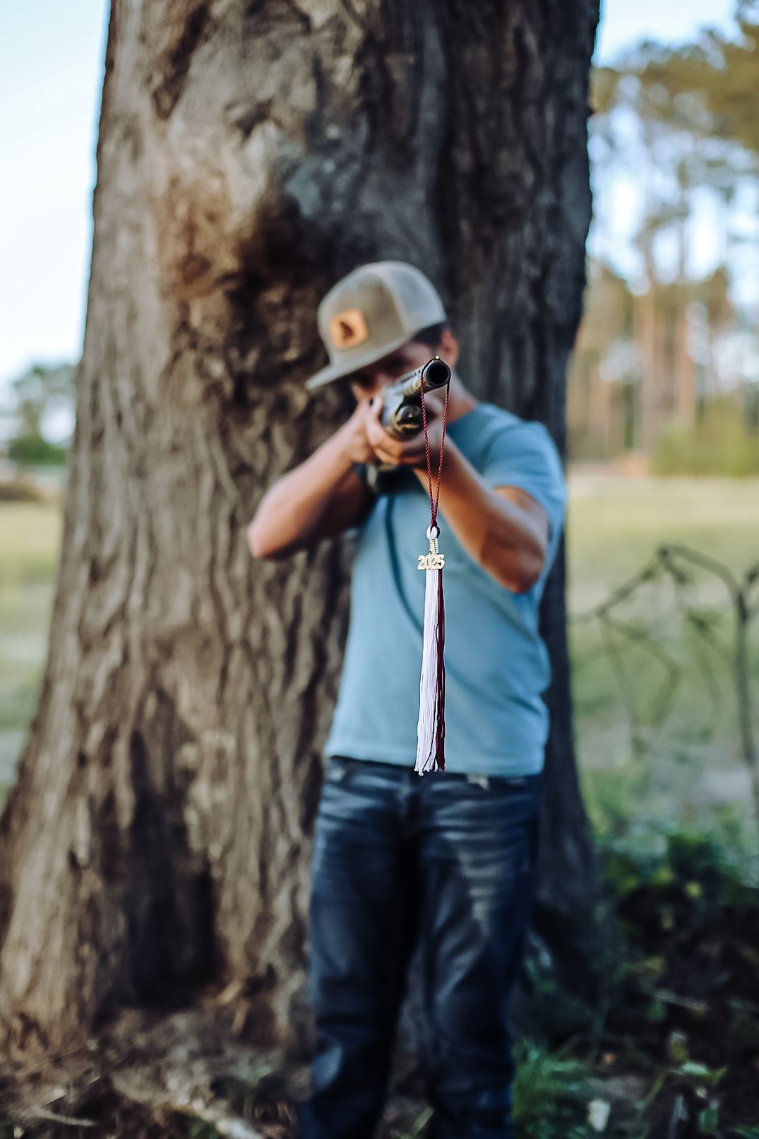 Photographer in blue shirt takes photos near a large tree trunk in an outdoor nature setting.