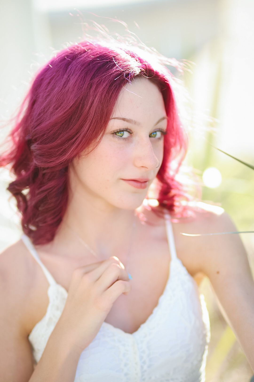 A dreamy portrait featuring magenta hair and white lace dress in soft natural lighting.
