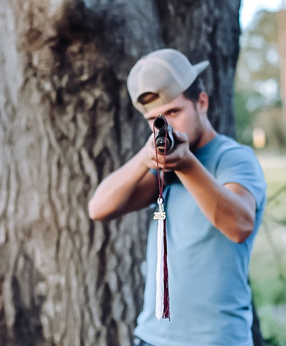 A person wearing a blue shirt and white cap takes a sip from a water bottle against a blurred forest background.