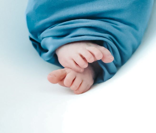 Tiny baby feet wearing blue socks against a white background in a soft, gentle composition.