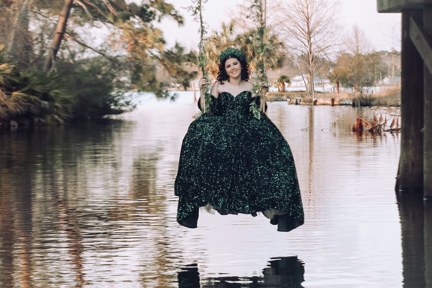 Woman in stunning green ballgown standing in flooded waters surrounded by trees.
